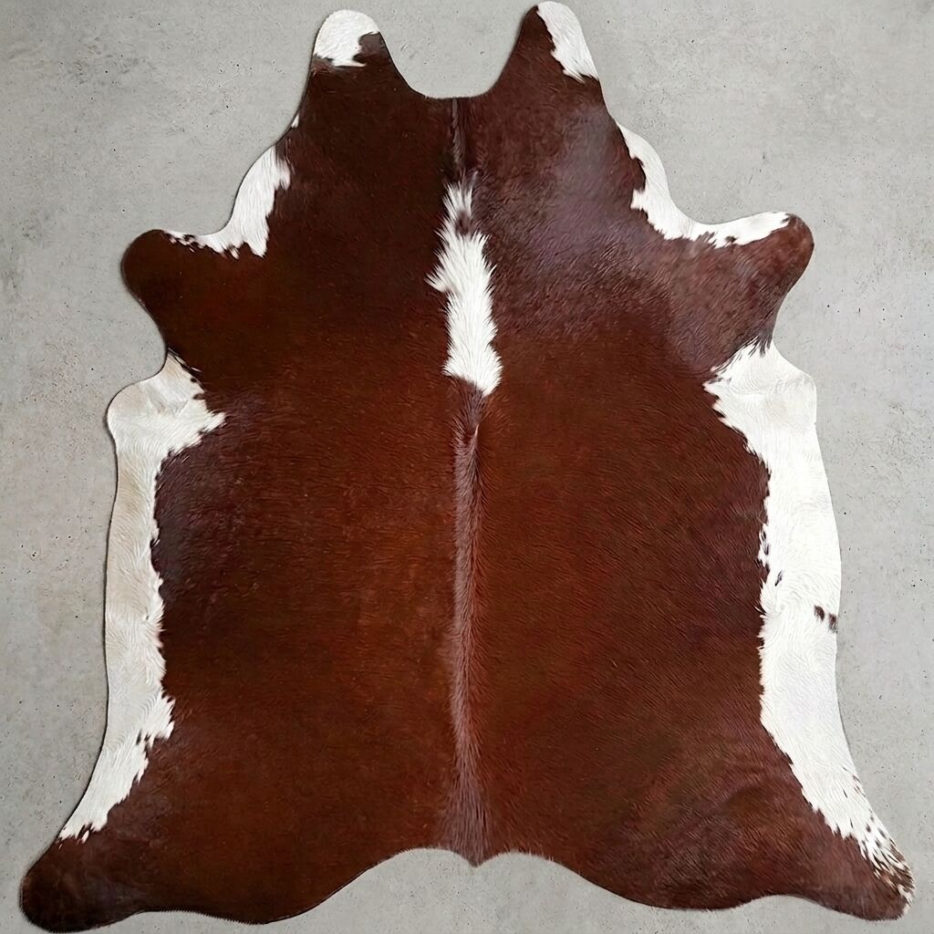 Peau de vache brune et blanche sur un sol clair.