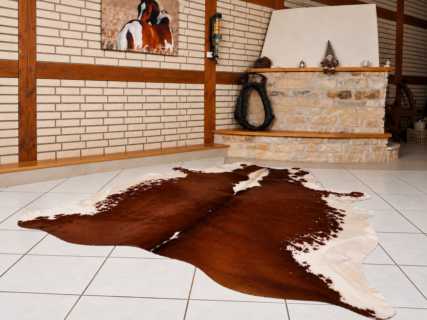 Peau de vache marron et blanche sur un carrelage clair dans une pièce rustique aux murs de briques, avec poutres en bois et éléments en pierre naturelle